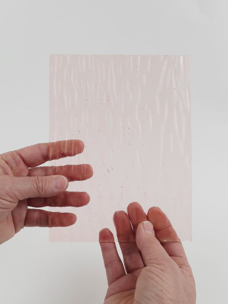 Video of the Blush Gentle Waves glass plate in transparent pink, 15x19cm, held up and tilted to show its pattern and transparency