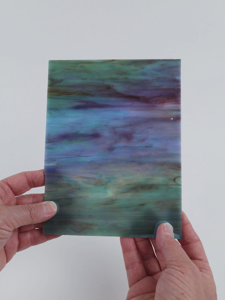 Video of the Azores Marbled Iridised glass plate in iridised translucent blue, 15x19cm, held up and tilted to show its pattern and transparency