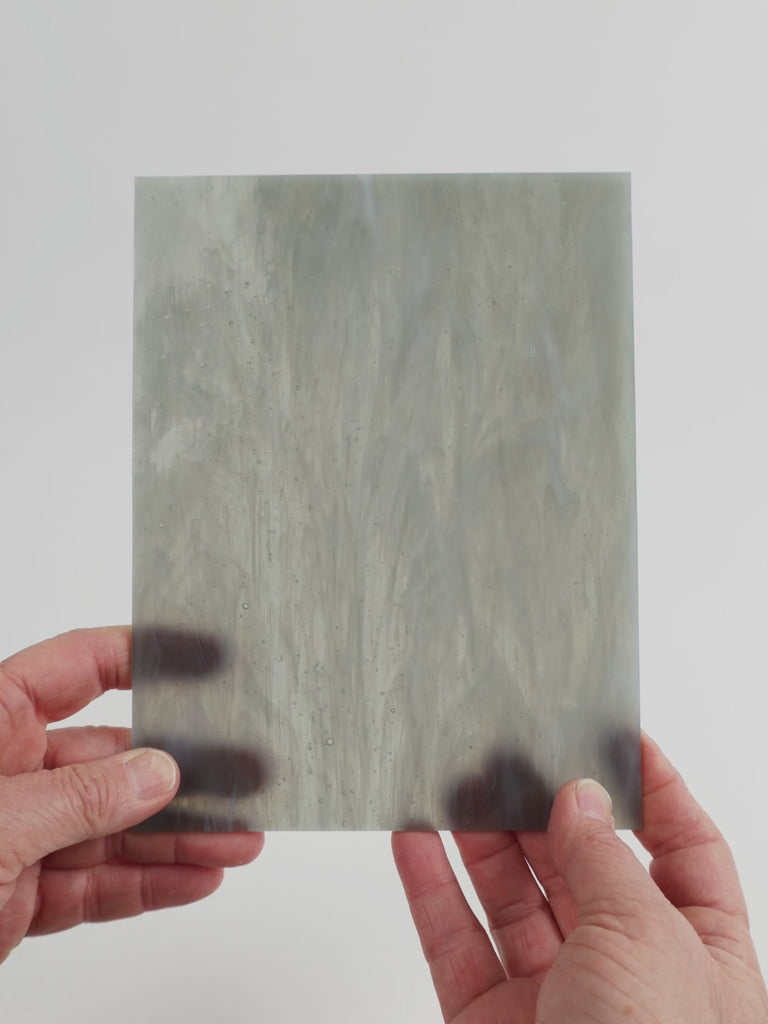 Video of the shadow wispy glass plate in grey translucent swirls, 15x19cm, held up and tilted to show its pattern and transparency