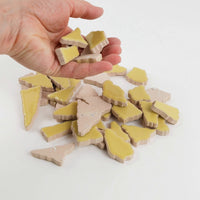 Video of Flip XL ceramic puzzle pieces in ochre yellow, opaque glazed porcelain, 20–60 mm, picked up from a pile by hand and dropped back to show their size, shapes and finish