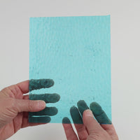 Video of the Water hammered glass plate in hammered transparent blue, 15x19cm, held up and tilted to show its pattern and transparency