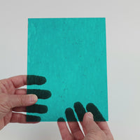 Video of the Dark Turquoise Hammered glass plate in hammered transparent turquoise, 15x19cm, held up and tilted to show its pattern and transparency