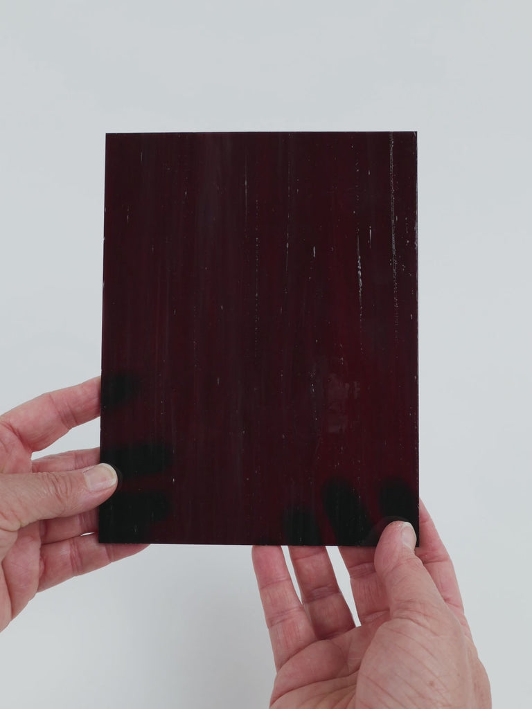 Video of the Plum Streaky glass plate in translucent purple, 15x19cm, held up and tilted to show its pattern and transparency